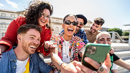 Gen Alpha, Gen Z y TikTok: siete conclusiones interesantes para las marcas Un grupo de amigos se ríe y se hace un selfie juntos, disfrutando de un entorno al aire libre.