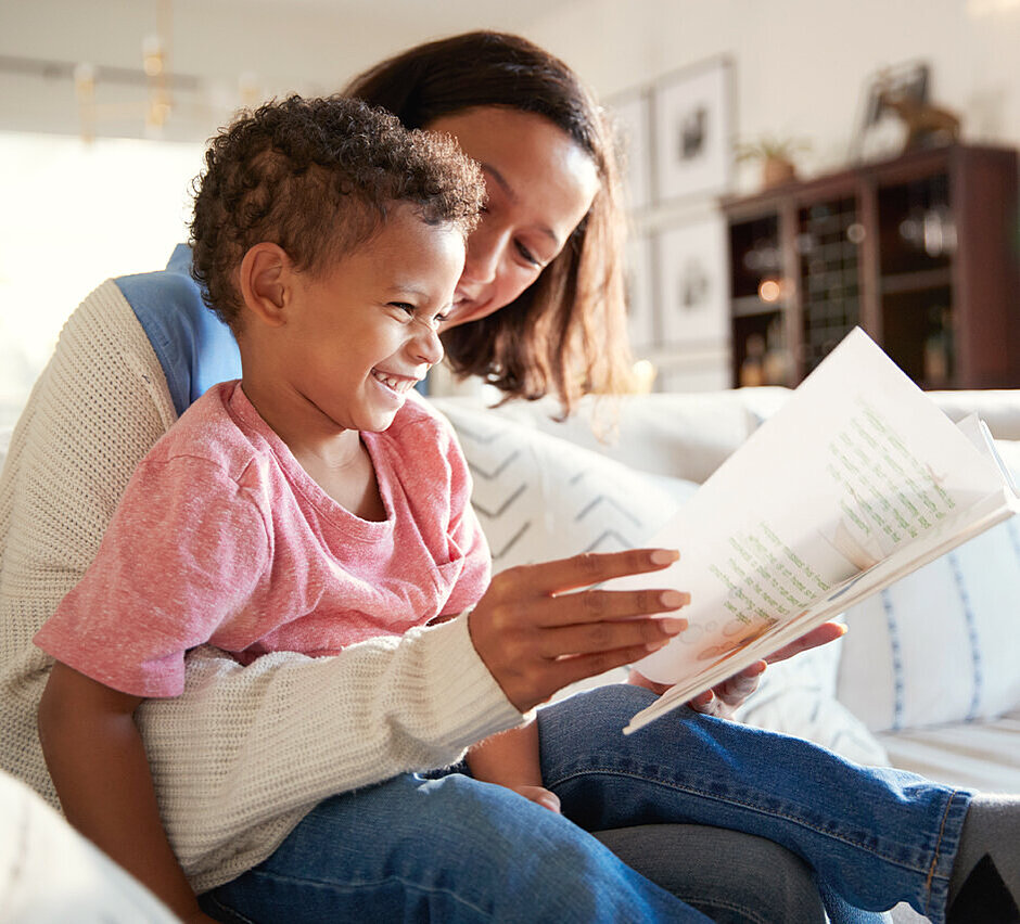 Mutter schaut mit ihrem Sohn auf dem Schoß zusammen in ein Buch