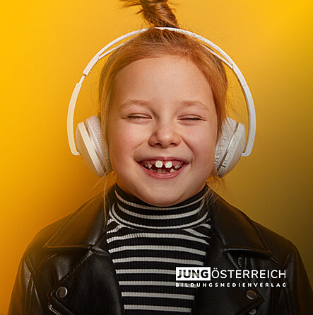 Mädchen, auf gelbem Hintergrund, lächelt während sie mit Kopfhörern ein Hörbuch hört.