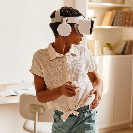 Kind trägt eine VR-Brille und läuft dabei mit Blick über seine Schulter durch einen Raum.