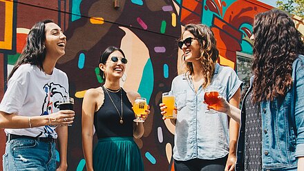 5 Proven Ways to Create and Develop the "Fun Factor" into Experiences for Young Consumers Four women are standing outside with a drink in their hands. The sun is shining and everyone is smiling.