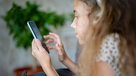 Mädchen blickt auf ein Smartphone.