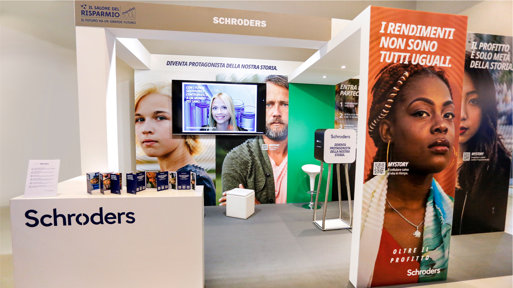 Stand di Schroders con lo slogan "Diventa protagonista della nostra storia" e schermi sugli investimenti sostenibili. Grandi ritratti e brochure illustrano il messaggio.