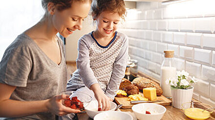 Frühstückstrends in der Familie Mutter bereitet mit ihrer kleinen Tochter in der Küche ein Müsli vor.