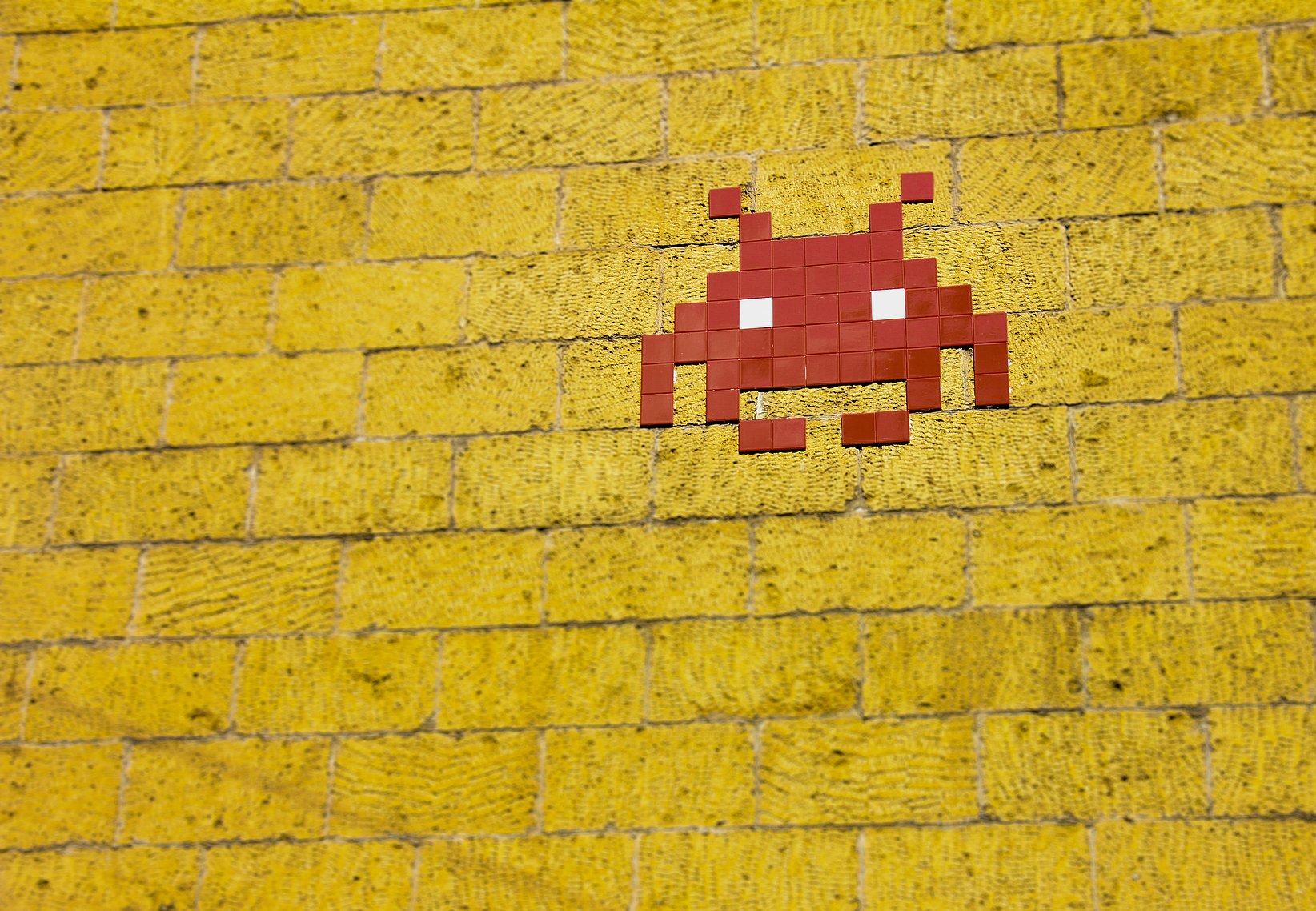 A red pixel figure on a yellow background, which reminds the viewer of the nostalgia of games.