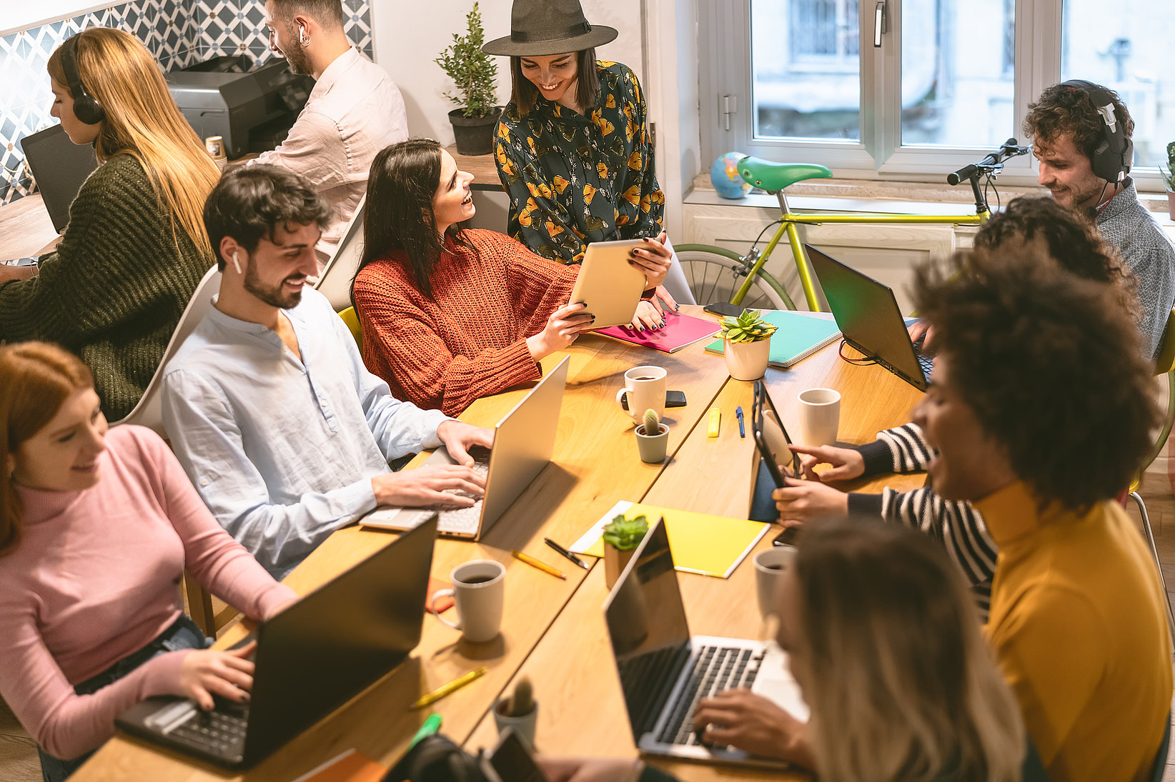 Grupo diverso de personas trabajando en laptops alrededor de una mesa en un entorno colaborativo de oficina.