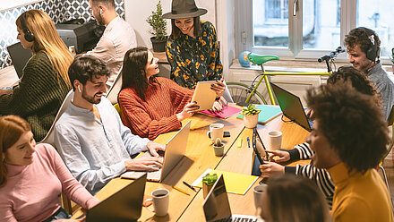 Cómo atraer jóvenes talentos: estrategias de Employer Branding para la Generación Z Grupo diverso de personas trabajando en laptops alrededor de una mesa en un entorno colaborativo de oficina.