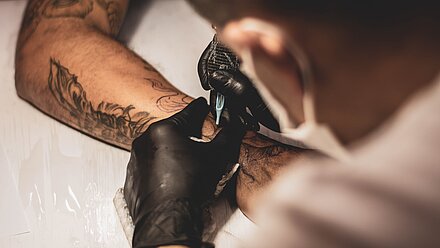 Brand Tattoos: Regret or Reclaim? A tattoo artist is about to engrave a new tattoo on a customer's arm.