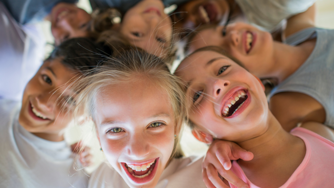 Un grupo de niños sonrientes se reúne en círculo, irradiando alegría y amistad mientras disfrutan de un momento feliz juntos.