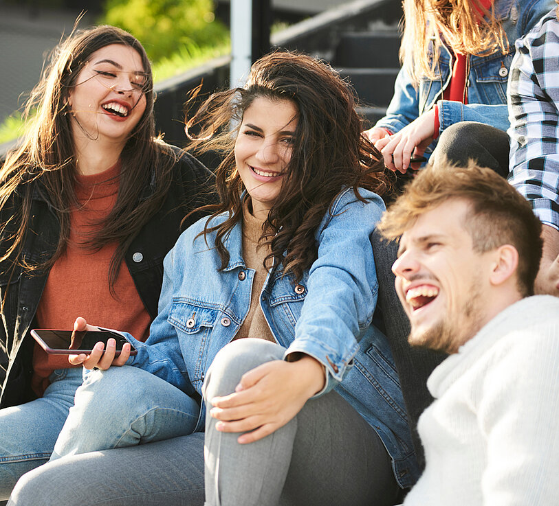 Gruppe Jugendlicher sitzt zusammen und lacht.