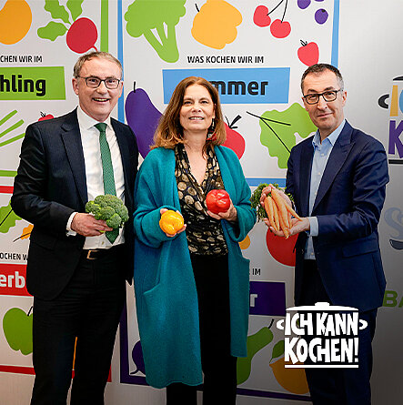 Zwei Männer und einer Frau mittleren Alters nebeneinanderstehend