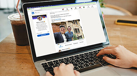 Personal Branding Person sitzt am Schreibtisch und sieht sich einen LinkedIn-Post am Laptop an.