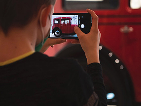 Junge fotografiert einen Oldtimer mit dem Smartphone.