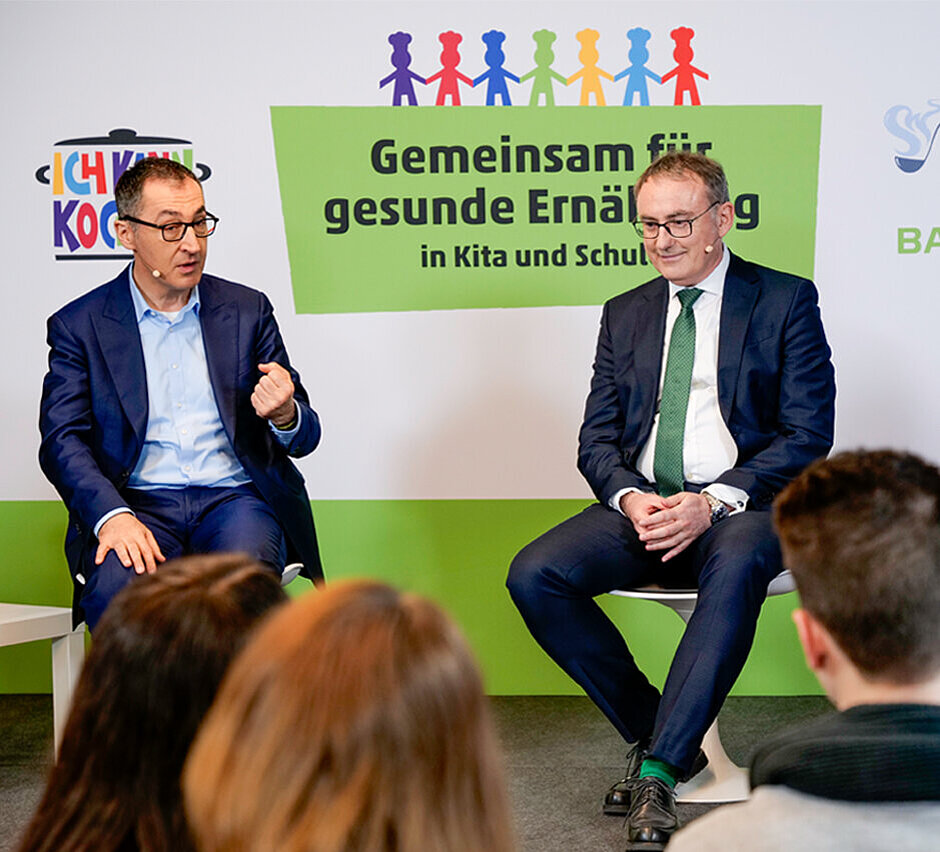 Zwei Männer mittleren Alters sitzen nebeneinander und unterhalten sich