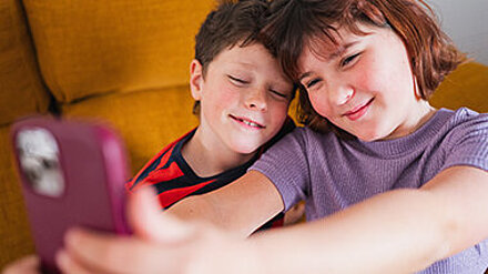 Gen A Part 2 Ein Junge und ein Mädchen posieren lächelnd für ein Selfie.