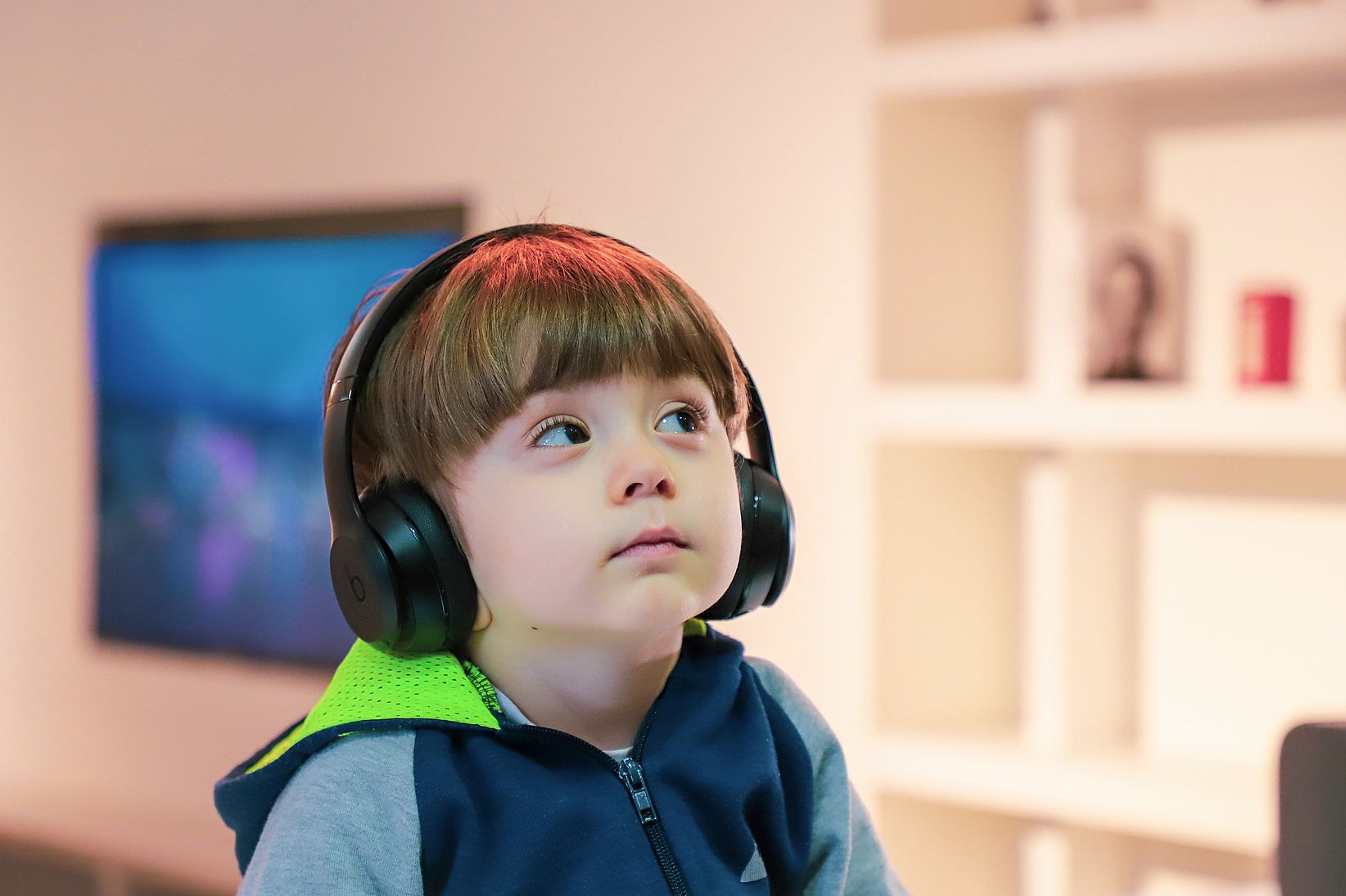A little boy listens to a podcast with a headset and has a curious look on his face.
