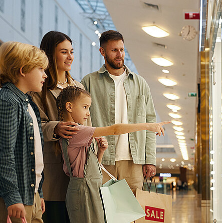 Familie in einer Shopping Mall vor einem Schaufenster