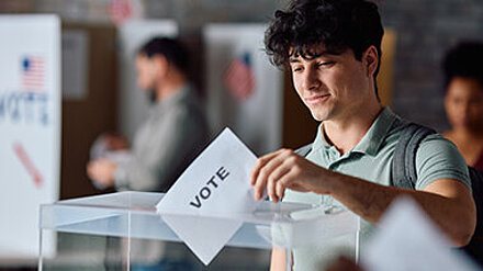 Gen Z und die Bundestagswahl 2025 Junger Mann wirft seine Stimme in eine Wahlurne.