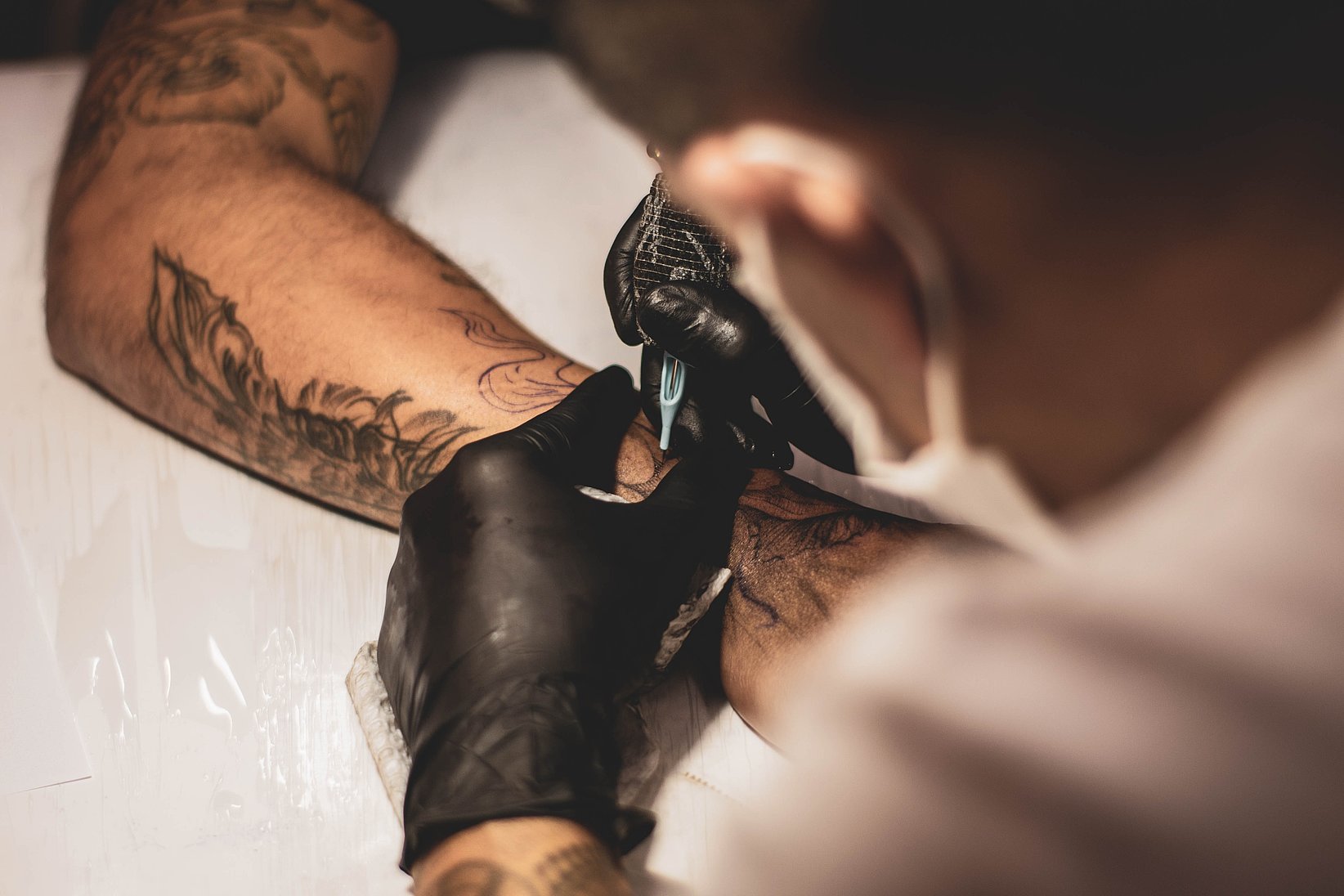 A tattoo artist is about to engrave a new tattoo on a customer's arm.