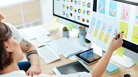 Creating for the Creators! Zwei Grafikdesignerinnen sehen sich gemeinsam ein Design auf dem PC an.