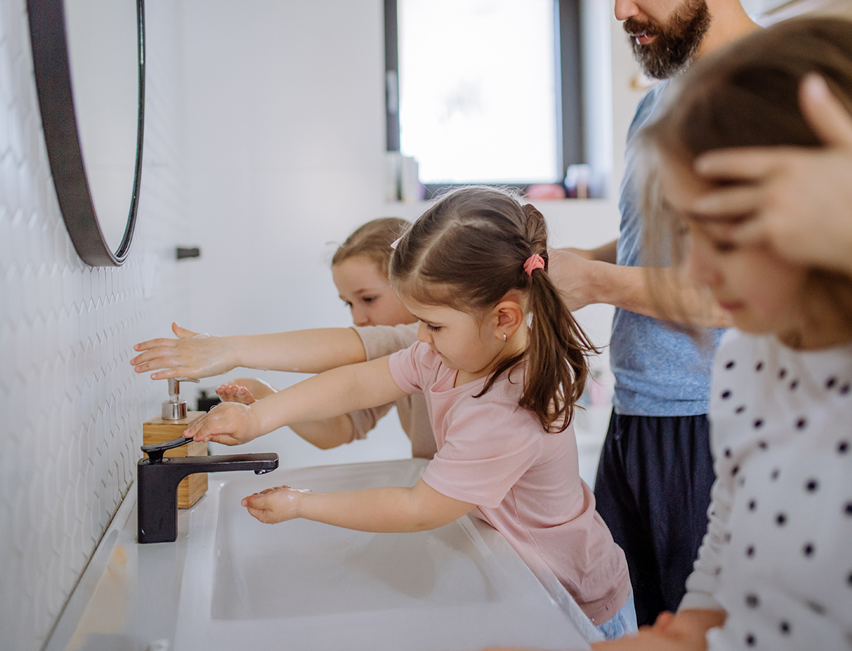 Vater und drei Töchter waschen im Bad ihre Hände.