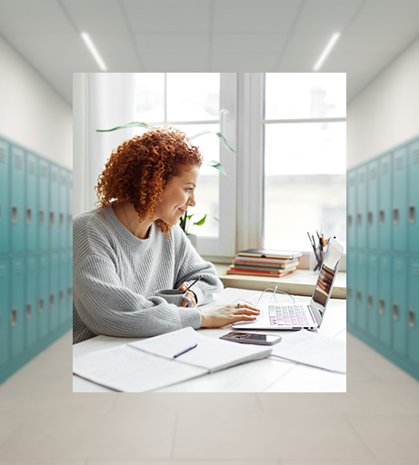Lehrerin sitzt lächelnd an ihrem Arbeitsplatz vor einem Laptop.
