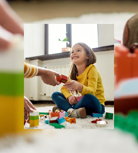 Mädchen sitzt auf dem Boden und spielt mit Bauklötzen