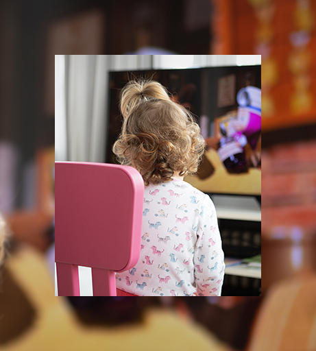 Mädchen sitzt auf einem Stuhl und sieht eine Spielzeugwerbung im Fernsehen.