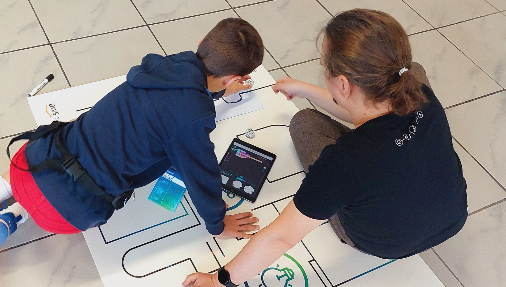 Ein junge und ein Mann sitzen auf dem Boden und schauen auf eine Zeichnung, die darauf liegt.