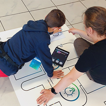 Ein junge und ein Mann sitzen auf dem Boden und schauen auf eine Zeichnung, die darauf liegt.