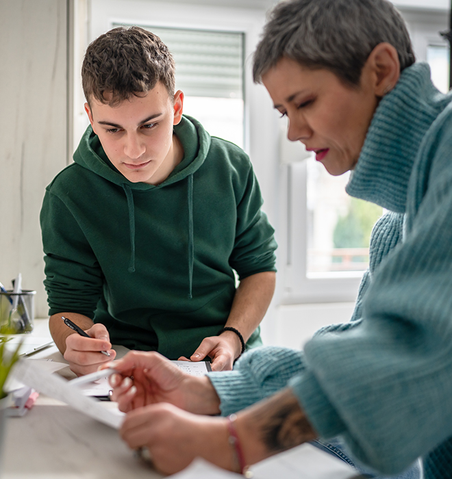 Mutter schaut mit ihrem Sohn gemeinsam auf ein Blatt Papier