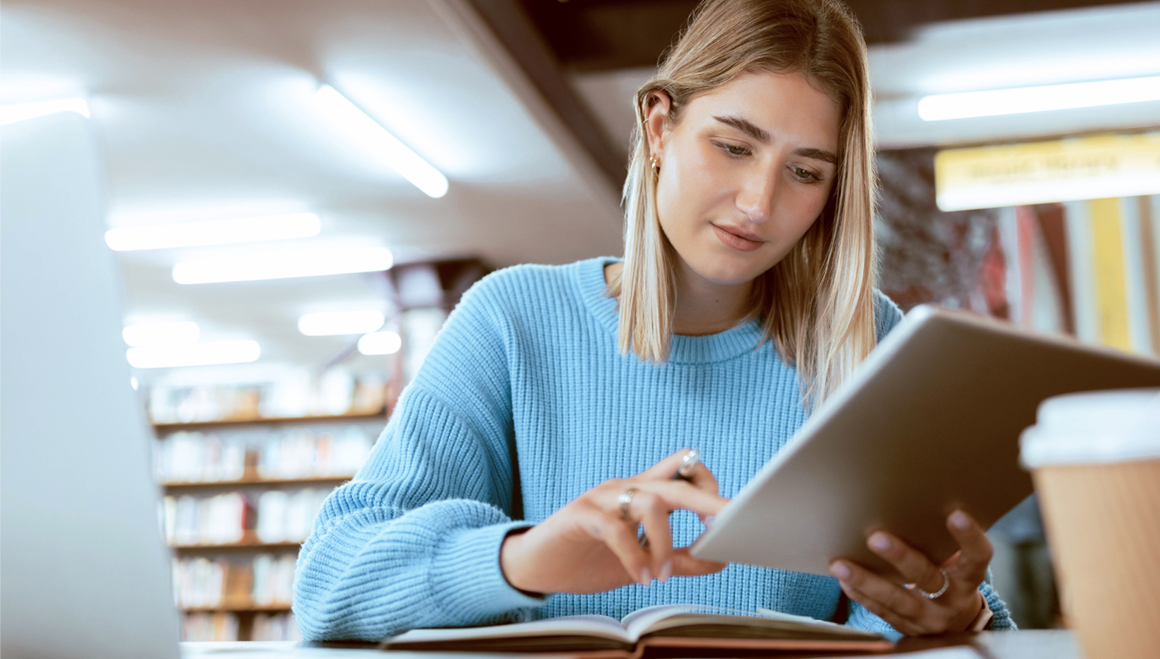 Junge Frau mit Tablet in der Bibliothek