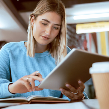Junge Frau mit einem Tablet in der Bibliothek