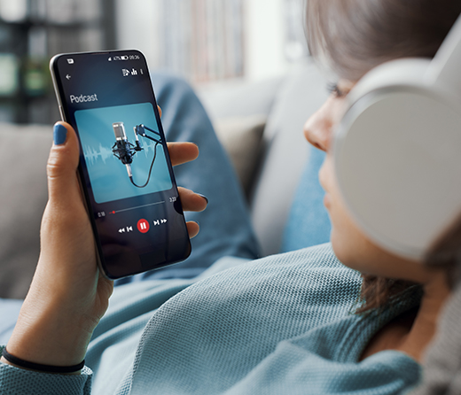 Junge Frau mit Kopfhörern und Handy in der Hand