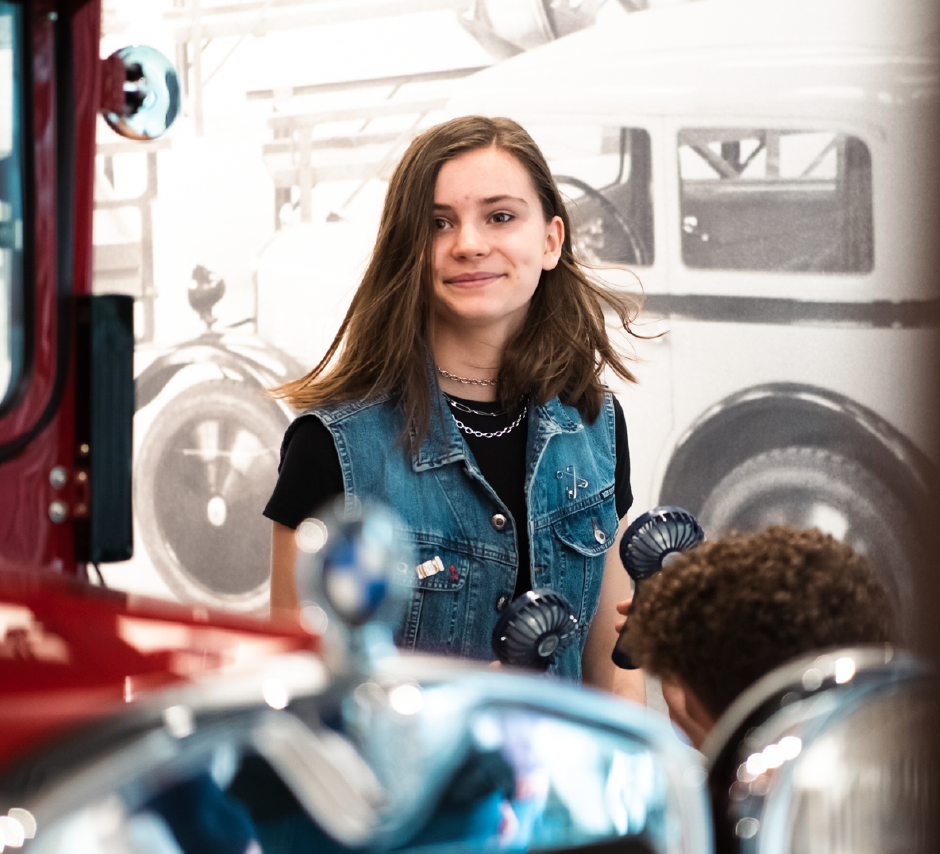 Lächelndes Mädchen zwischen Fahrzeug-Exponaten