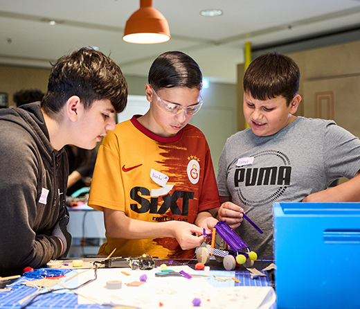 Jungs tüfteln an einem Modellauto in vereinfachter Form aus Holz
