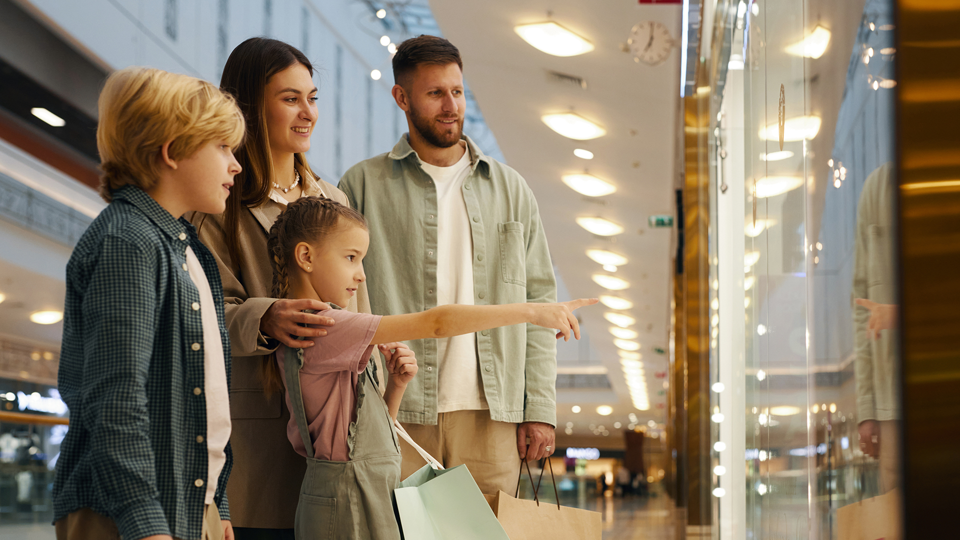 Familie in einer Shopping Mall vor einem Schaufenster
