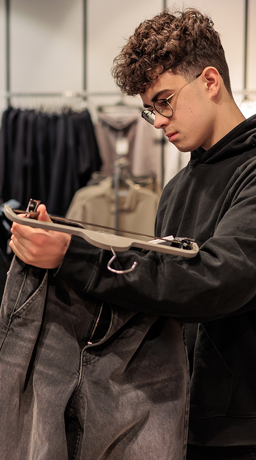 Jugendlicher betrachtet eine Jeans in Bekleidungsgeschäft