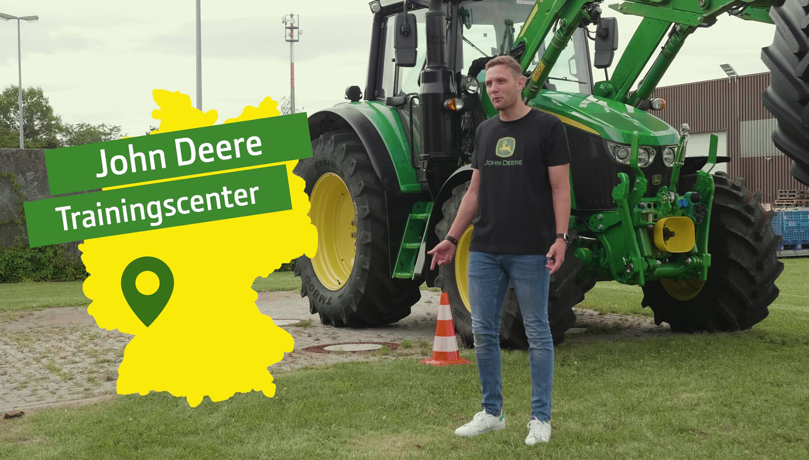 Mann steht vor einem großen grünen Traktor