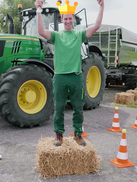 Mann steht aufrecht auf Strohballen und streckt die Arme in die Höhe