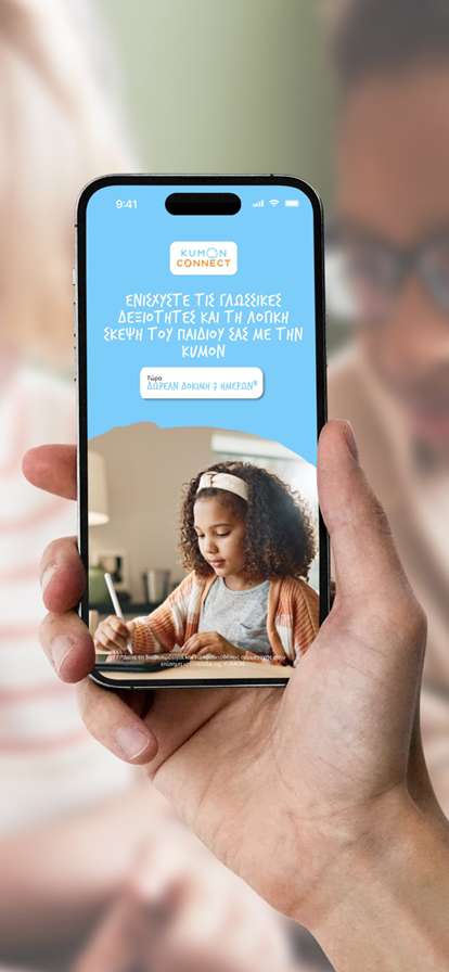 Hand mit Smartphone, das KUMON Connect App zeigt, vor Lernsituation mit Kindern und Lehrerin.