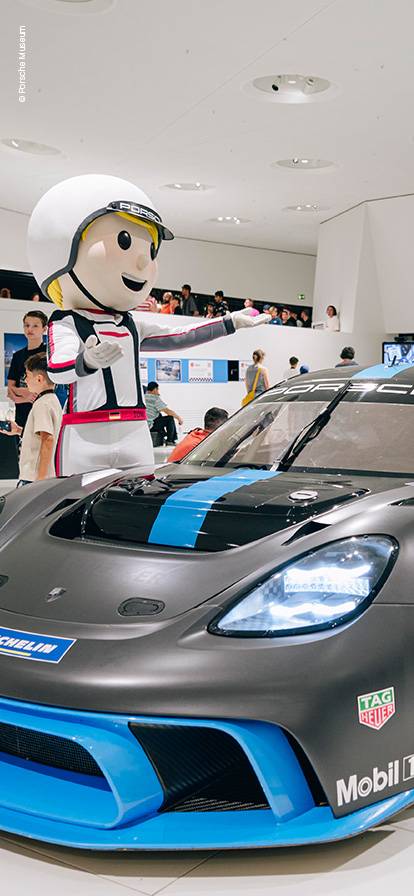 Zwei Rennfahrer-Maskottchen stehen an einem Porsche 