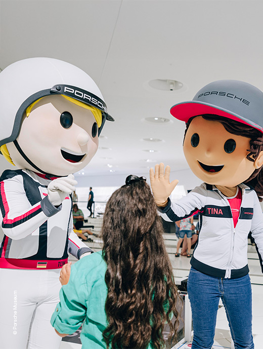 Zwei Rennfahrer-Maskottchen sprechen mit einem Kind