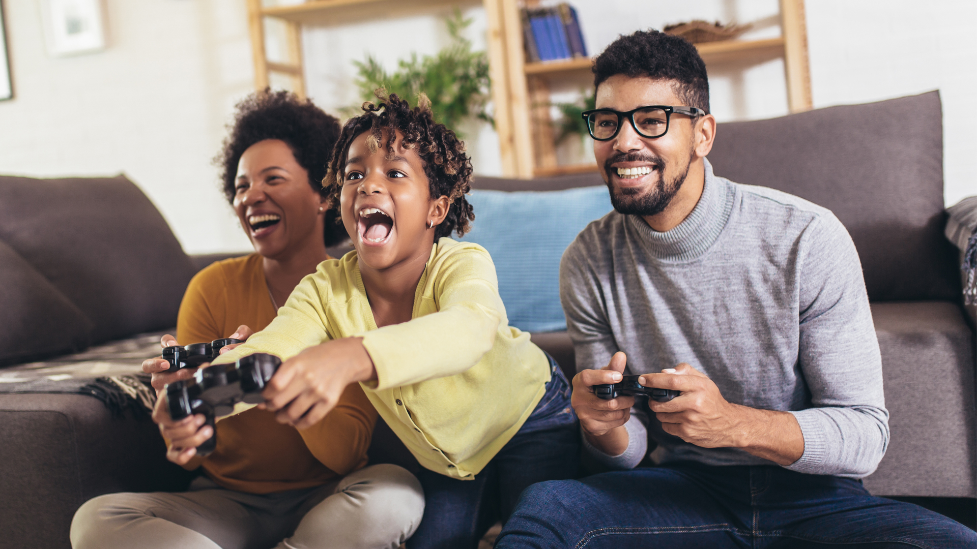 Eltern spielen mit ihrem Sohn ein Videospiel und lachen