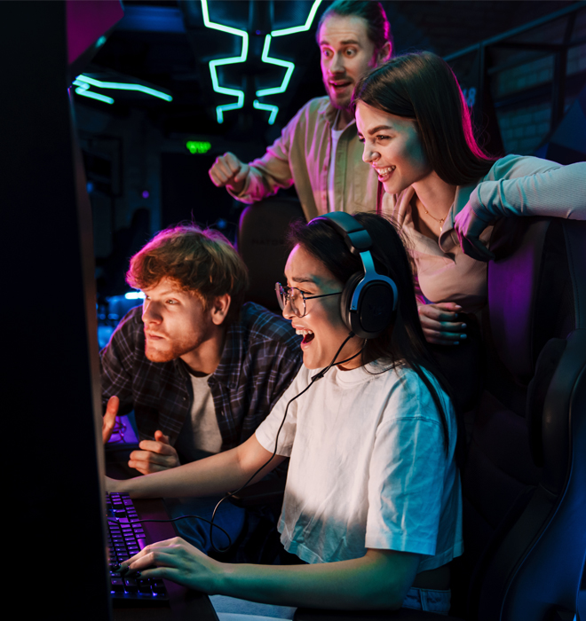 Gruppe Jugendlicher sitzt vor Bildschirm im Dunklen mit Neonlichtern.