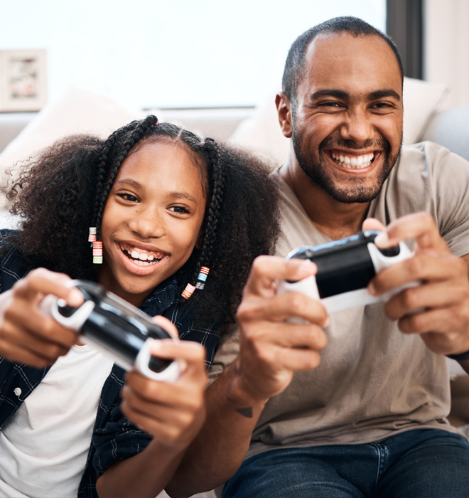 Vater und Tochter halten einen Spielecontroller in der Hand.