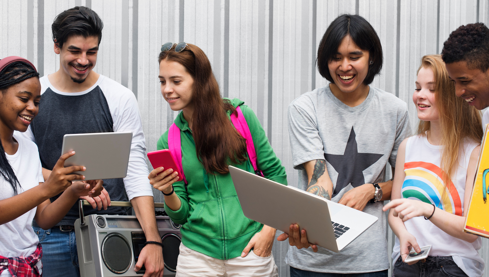 Gruppe Jugendliche sitzen mit Laptop zusammen und lachen.