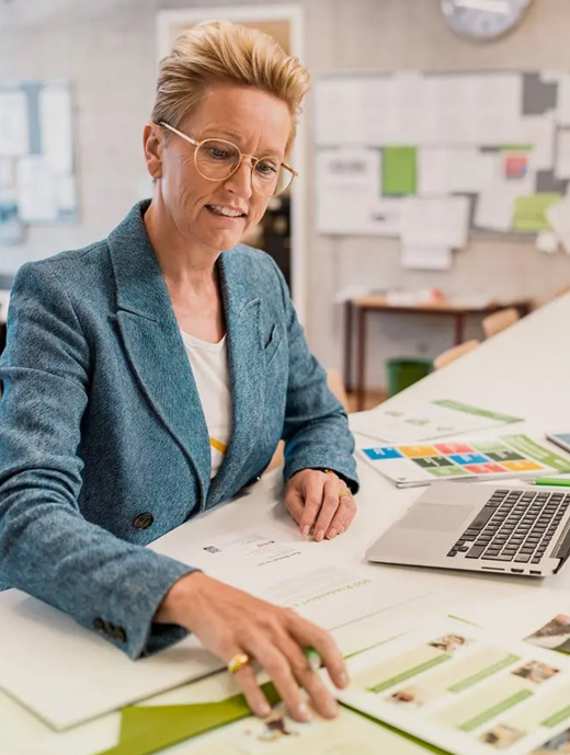 Lehrerin sortiert Unterlagen an ihrem Schreibtisch.