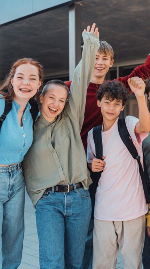 Gruppe Schüler steht lachend vor einem Gebäude.