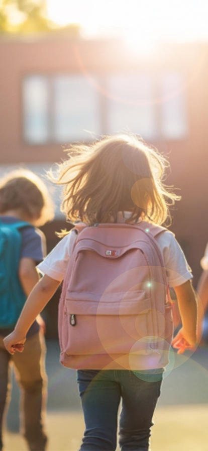 Kleines Mädchen rennend von hinten mit einem rosa Rucksack auf dem Rücken